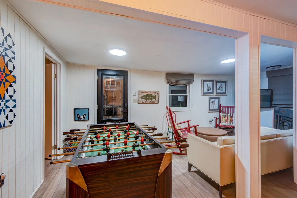 The focal point is a foosball table accompanied by a playful red rocking chair and lively wall art, creating a fun, casual vibe ideal for kids and teens. The setup encourages friendly competition and interactive entertainment.