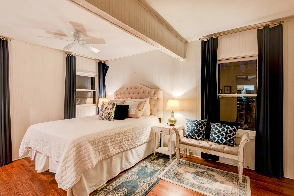 A comfortable bedroom with a plush bed, bedside lamp, small seating area, and soft rug. The inviting setup is perfect for unwinding after a full day, offering a peaceful retreat for restful nights.