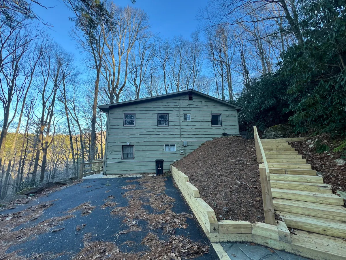 The exterior of the house with a wooden staircase leading up to a porch, surrounded by lush trees. The image evokes a welcoming entryway and a connection between the cabin and the outdoors, highlighting the ease of stepping right into the heart of Valle Crucis’s charm.